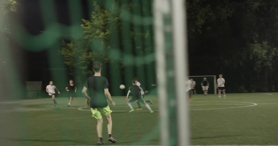 A group of men playing soccer at night