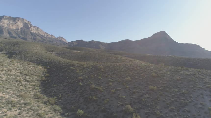 Aerial view of desert scrub in front of mountains
