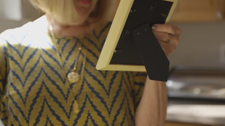 Woman picking up and looking at a framed picture