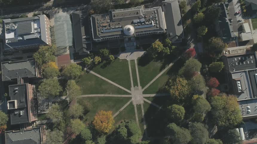 Several very large buildings surrounding a park in the fall