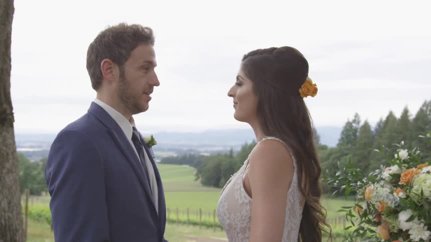 A bride and groom look at each other on a ranch at day