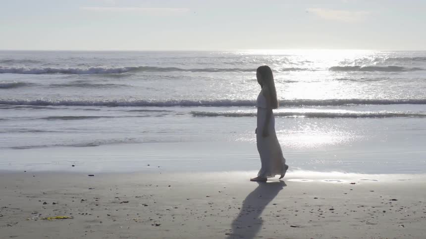 A woman is walking on the beach during daytime