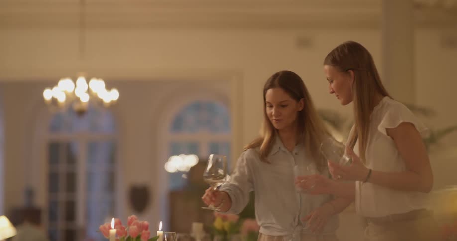 Two women placing glasses on a table