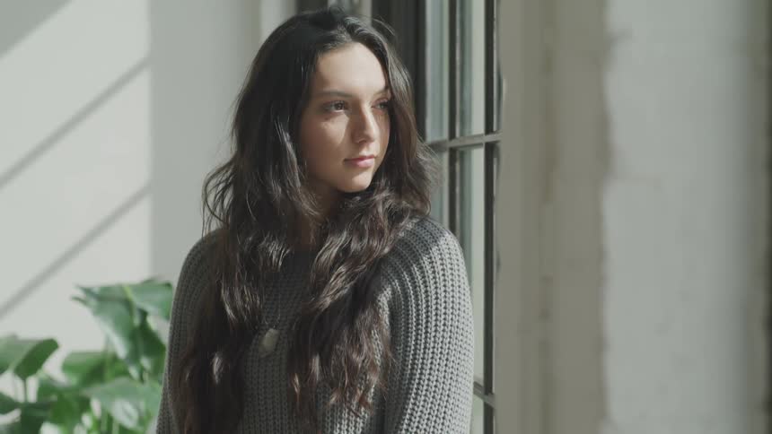 Woman sits looking out window