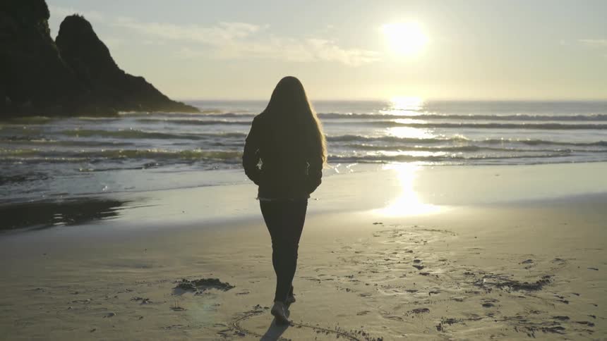A woman is walking by the beach