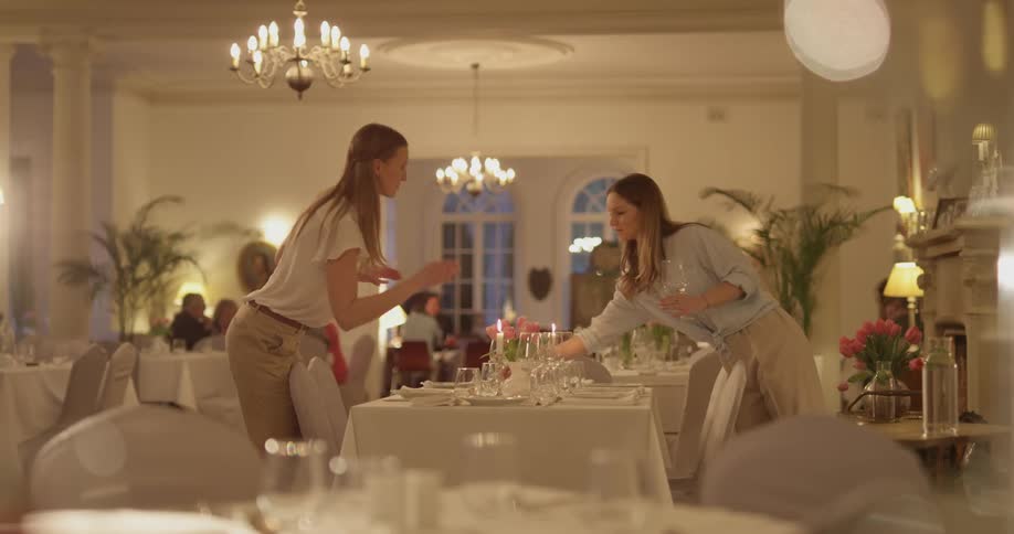 Two women place glasses down on a table