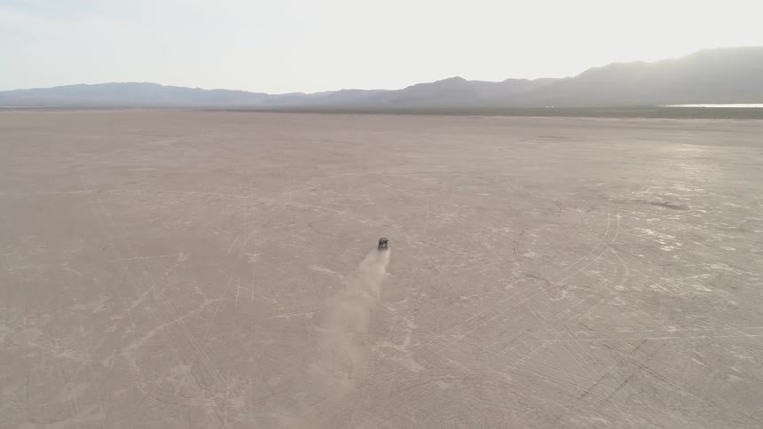 A vehicle is racing through an open desert