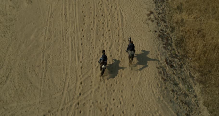Two men are riding horses in the dirt