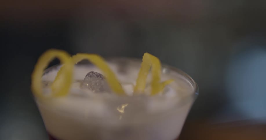 Someone is placing a lemon peel on a drink