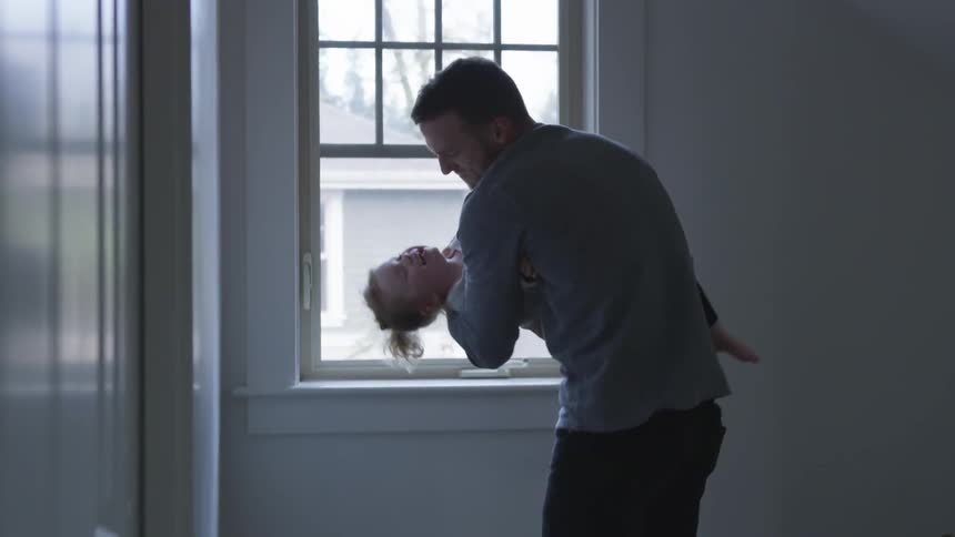 Man laughs with younger girl that he rocks up and down