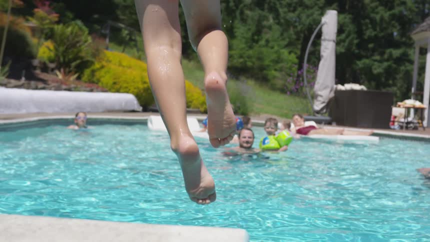 A young boy jumping into a pool