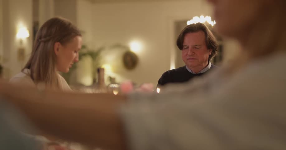 A family eats dinner and drinks wine at a table