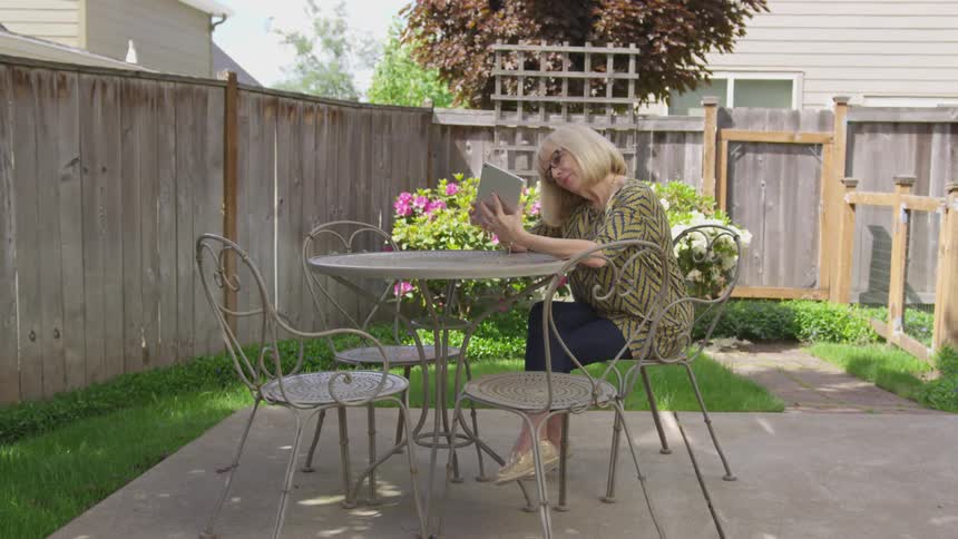 Woman uses table while sitting at patio table outside