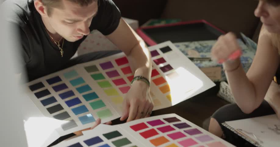 A man is looking through a color sheet with another person