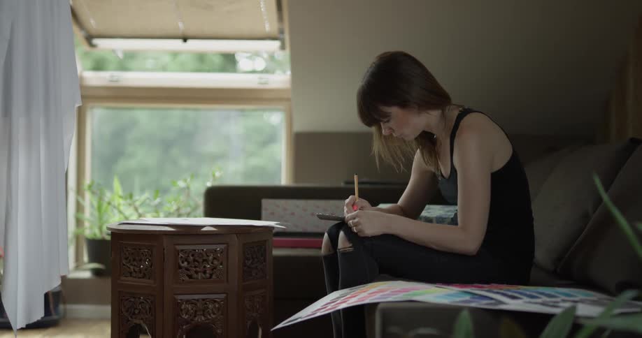 A woman is drawing while sitting on a bed