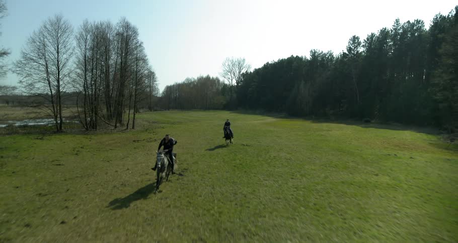 Two horses are ridden through the field