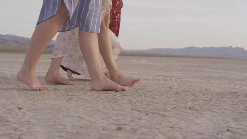 Three people walk across the sand