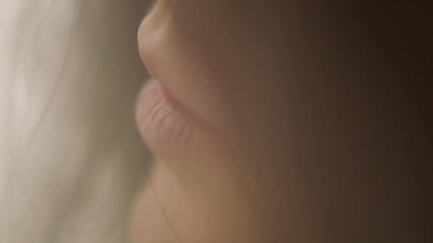 A woman's hair being blown away from her face my her mouth