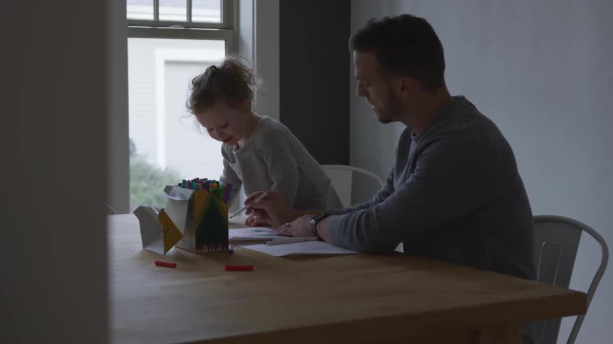 A father and daughter sitting at a table drawing
