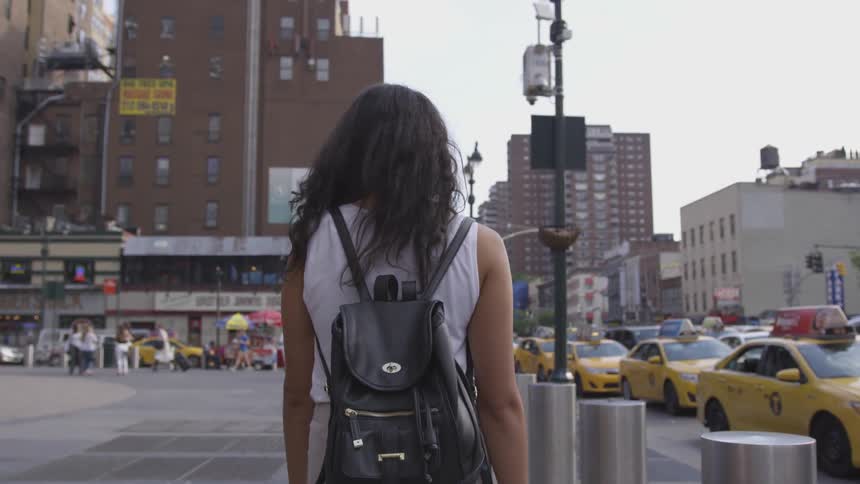 Woman wearing a backpack walking down a sidewalk