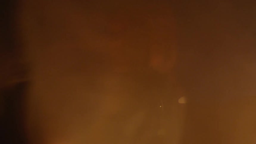Two people stand as smoke billows at them from the side