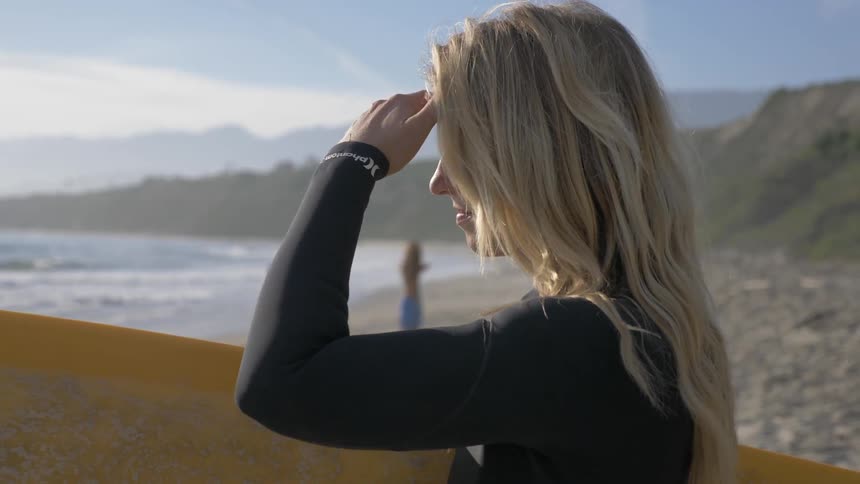 A woman holding a surfboard at the beach
