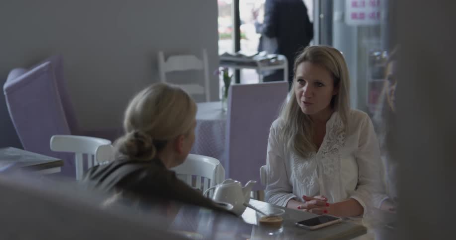 Two woman are talking seated at a table