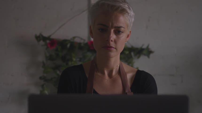 A woman with short cropped hair sits in front of a laptop