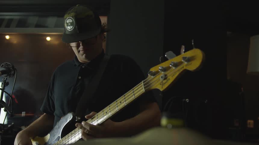 Man plays electric bass guitar in recording studio