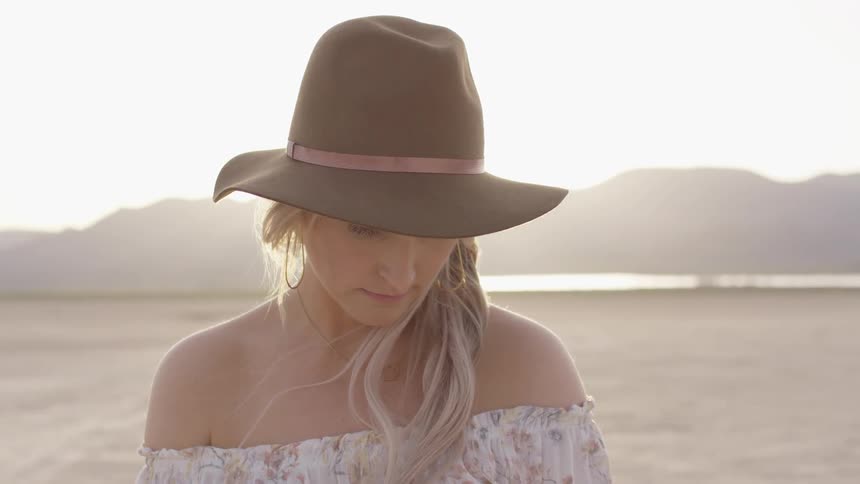 A woman stands with her back to a sunset on a beach