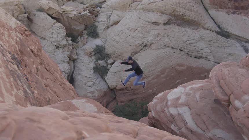 A man jumping off rocks in a canyon