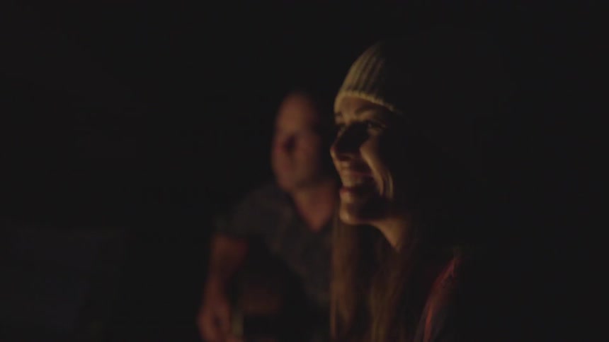 A woman laughing while a guy plays guitar