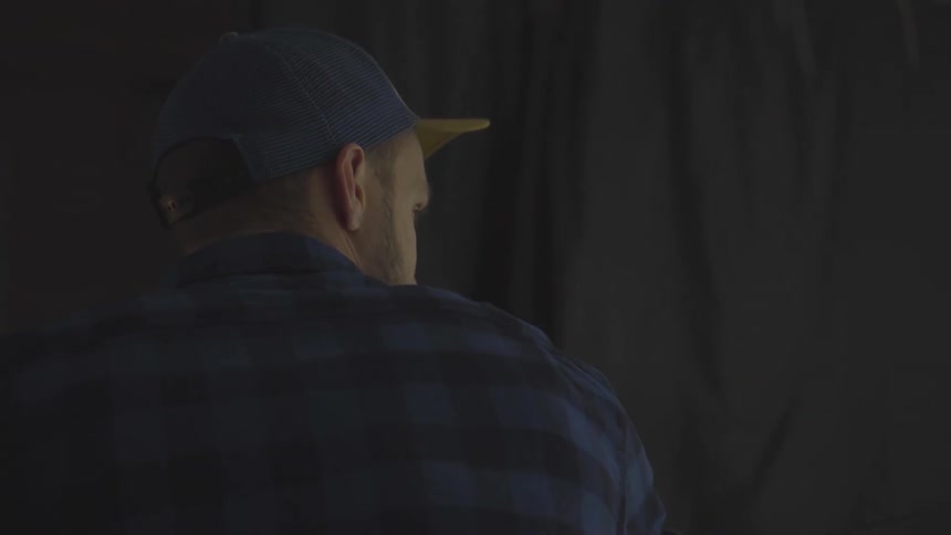 A man wearing a hat carries something heavy