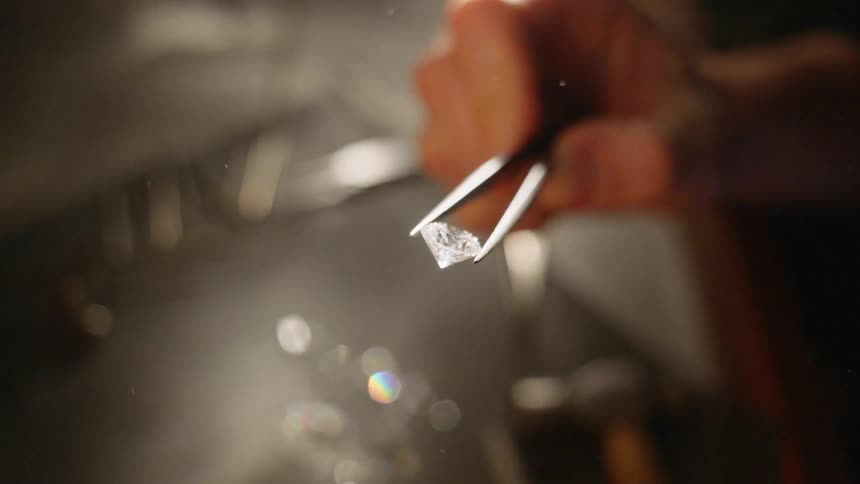 A person is holding a diamond with a tweezers