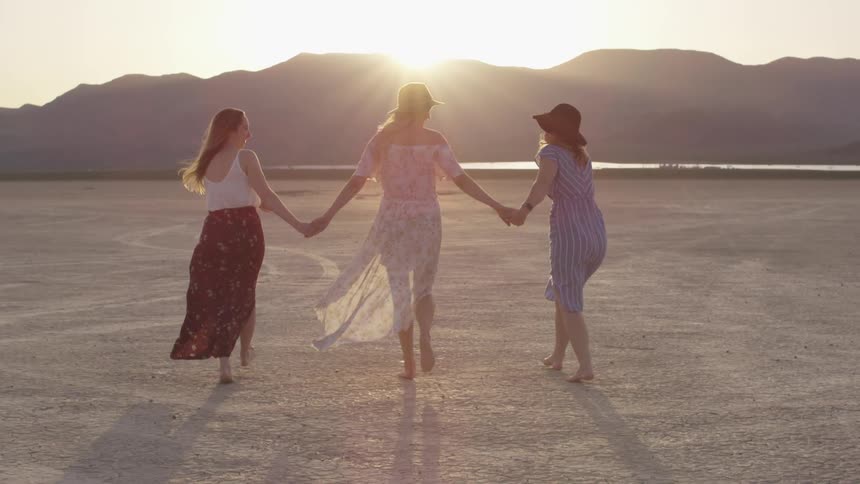 Three women hold hands while walking