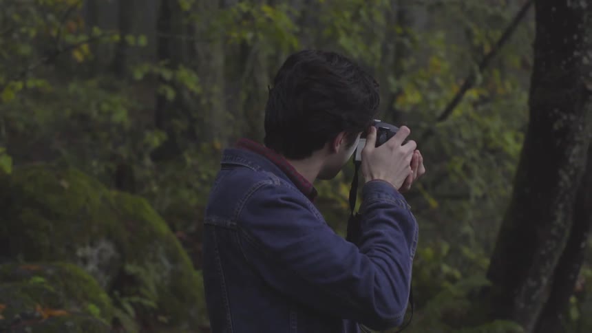 Man uses camera in forest