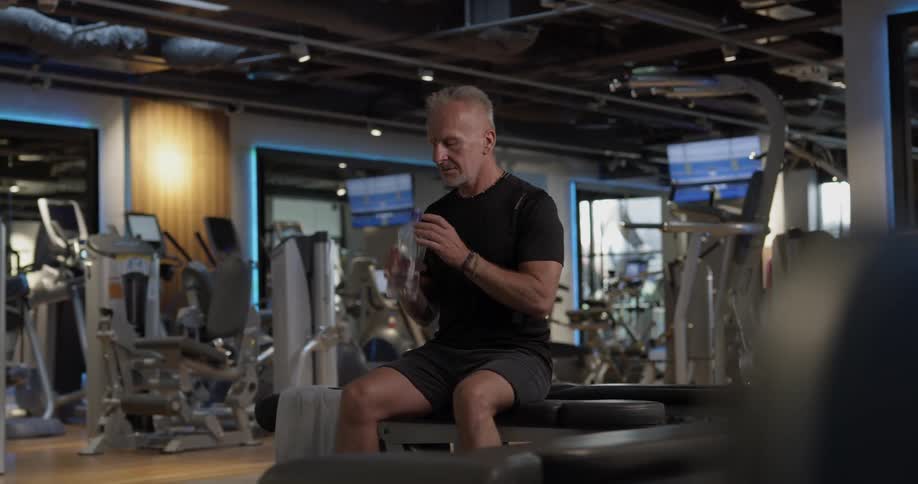 A man is in a gym and drinking water