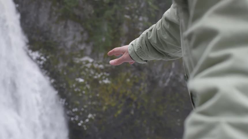 Person points reaches toward waterfall