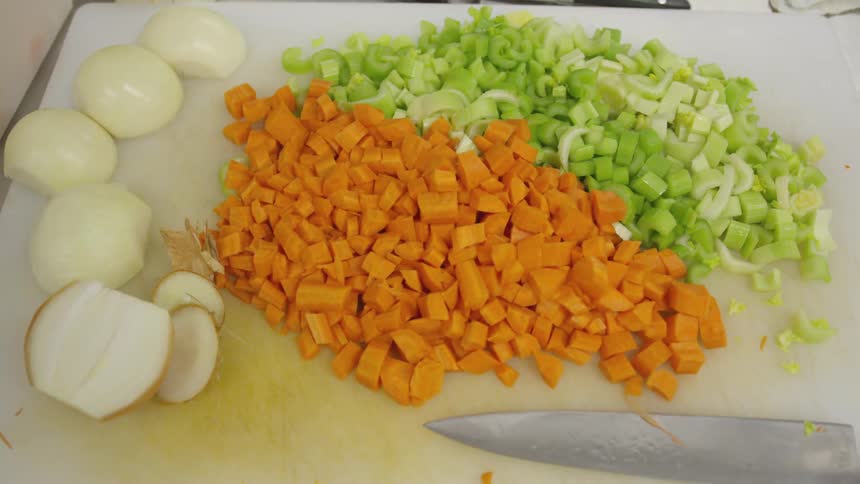 There are chopped vegetables next to a knife on a cutting board