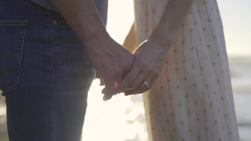 A man and woman are holding hands by the beach
