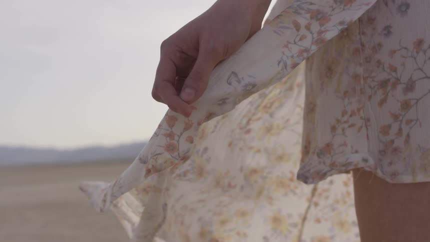 Woman wearing a flowing floral dress standing in a dry desert bed