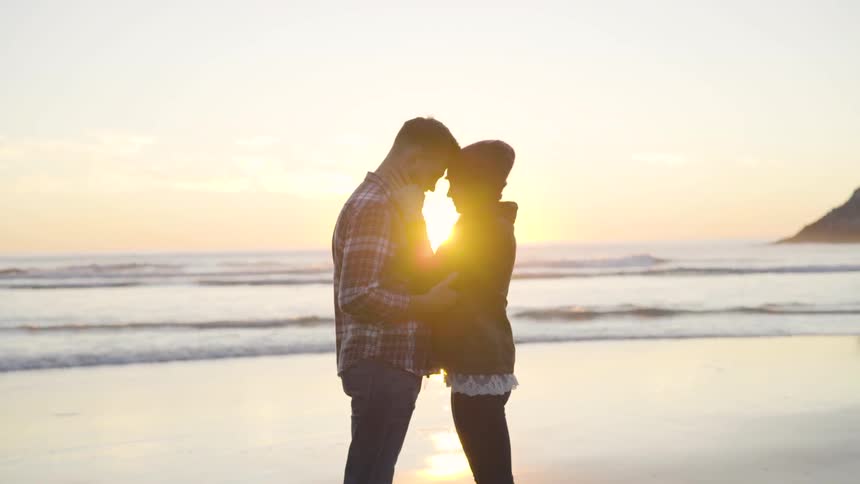 A man and woman kissing on the beach