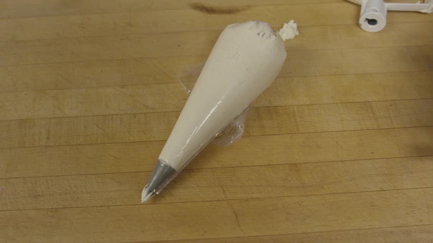 A tube is filled with icing and is on a table