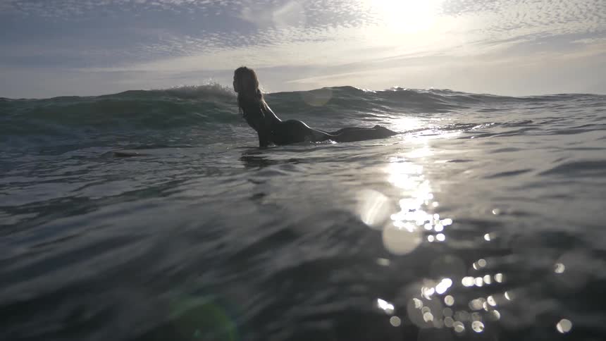 Woman laying on a surfboard in the sea