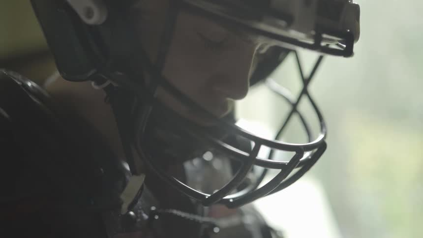 A young man with a football helmet is seen indoors with the bright sunlight shining through a window