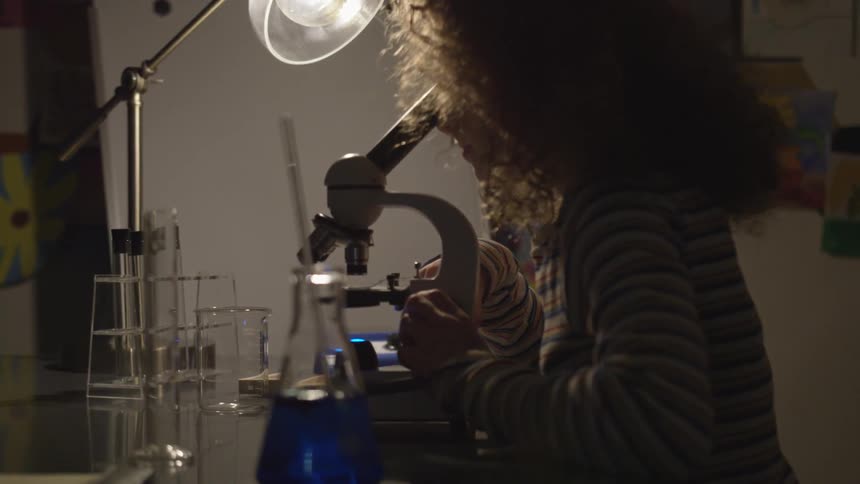 Girl looking through a microscope in a lab setting