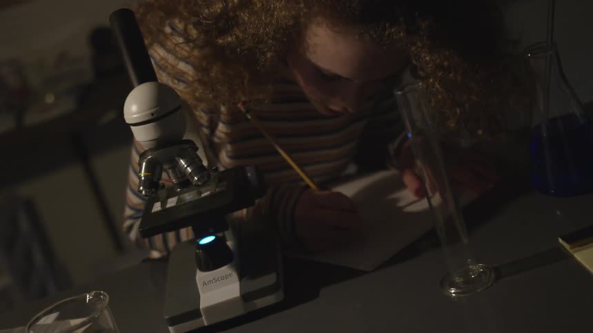 A woman writing in a book in a lab