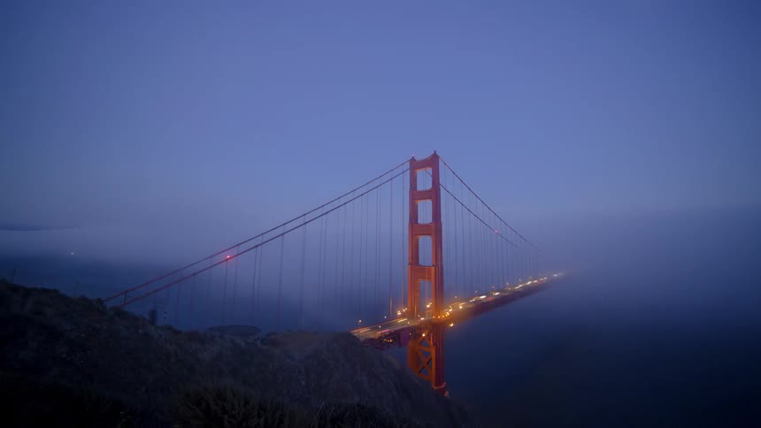 A lot of cars driving over a bridge at night