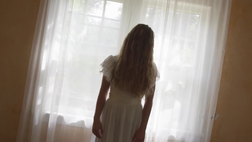 Woman with hair over her face in front of a window