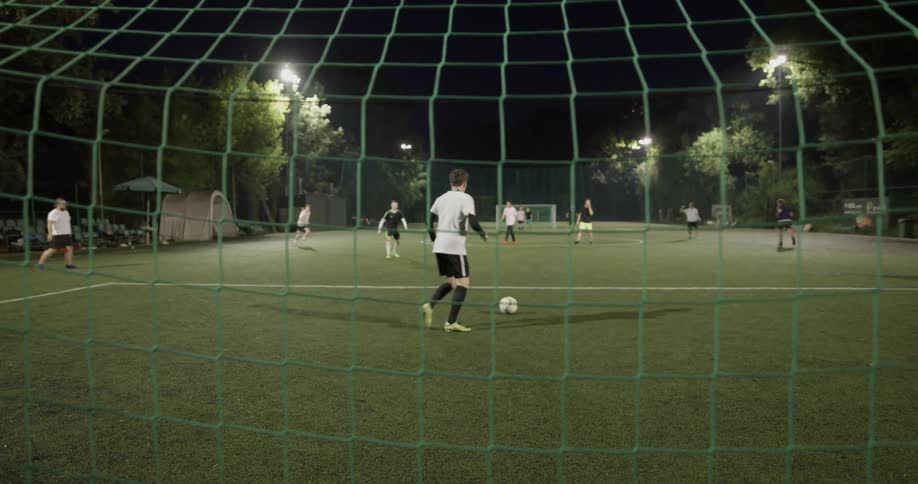 A group of people playing soccer on a field at night